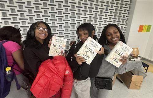 3 girls holding a book smiling